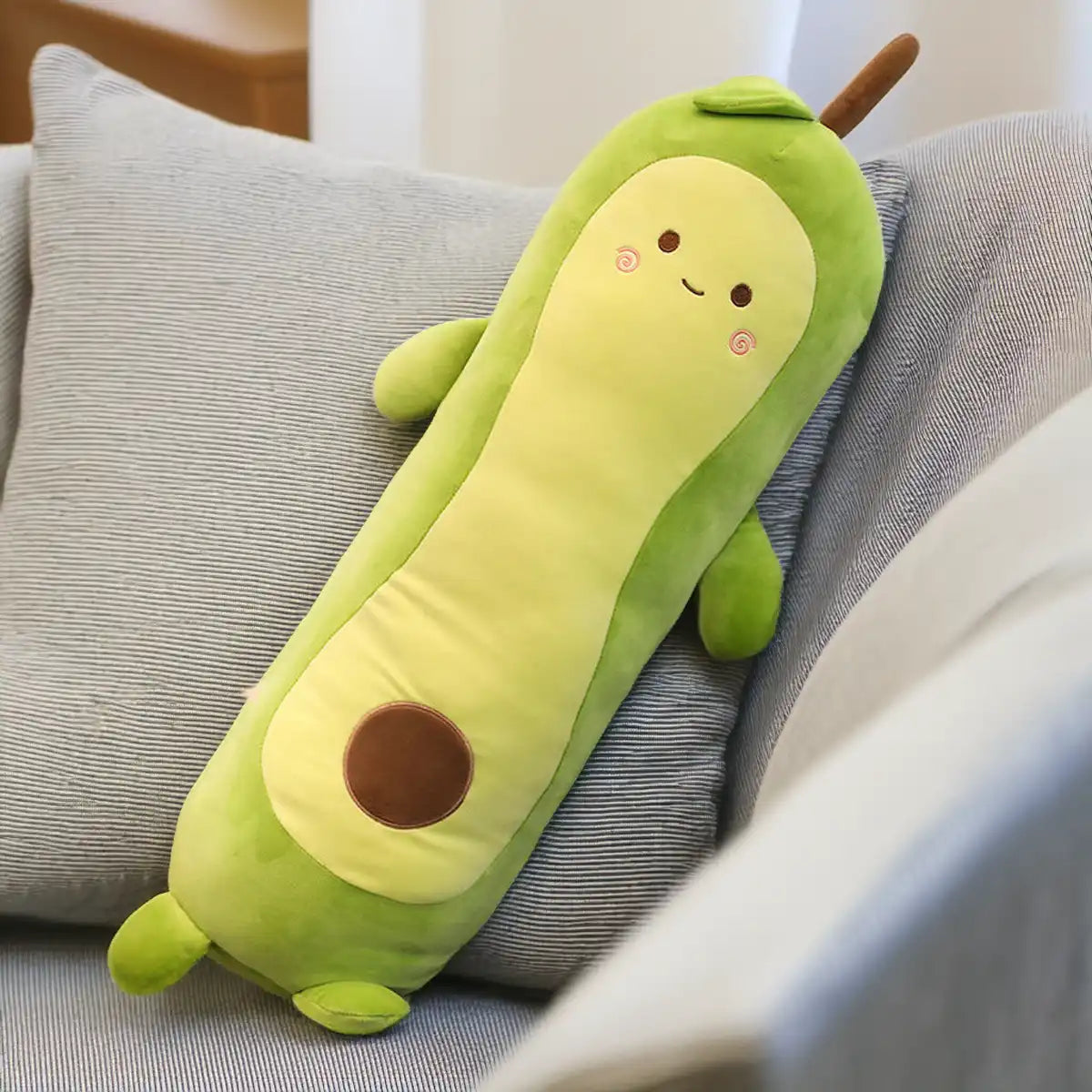 Una almohada de peluche de palta kawaii sobre un sillón color gris