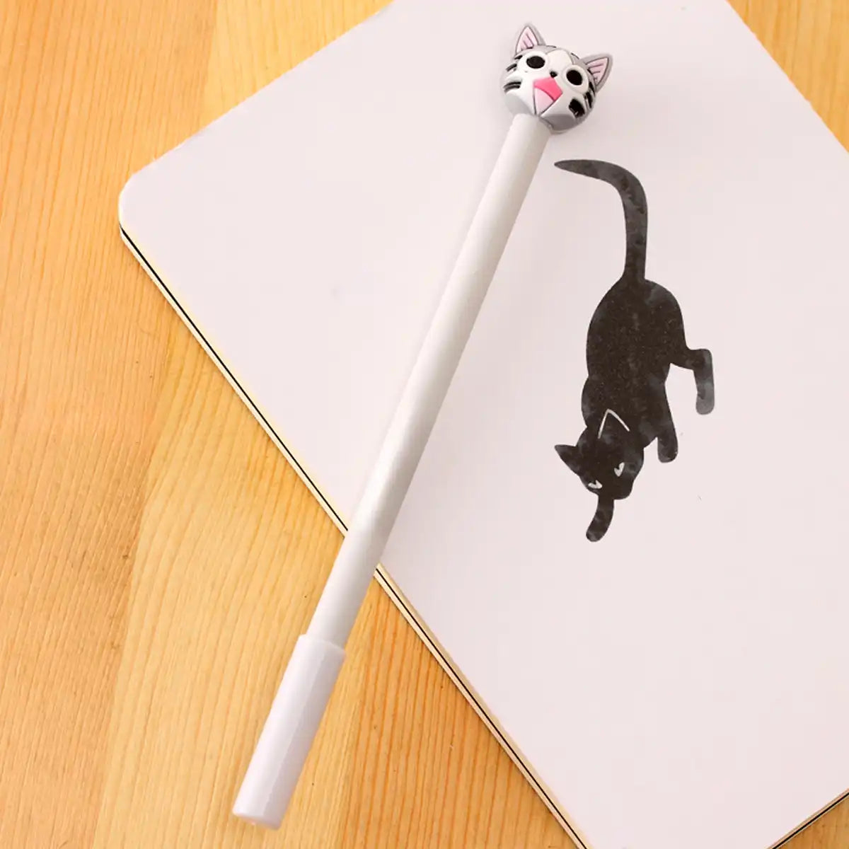 1 lápiz de gatito con carita feliz encina de un cuaderno con un gato negro dibujado