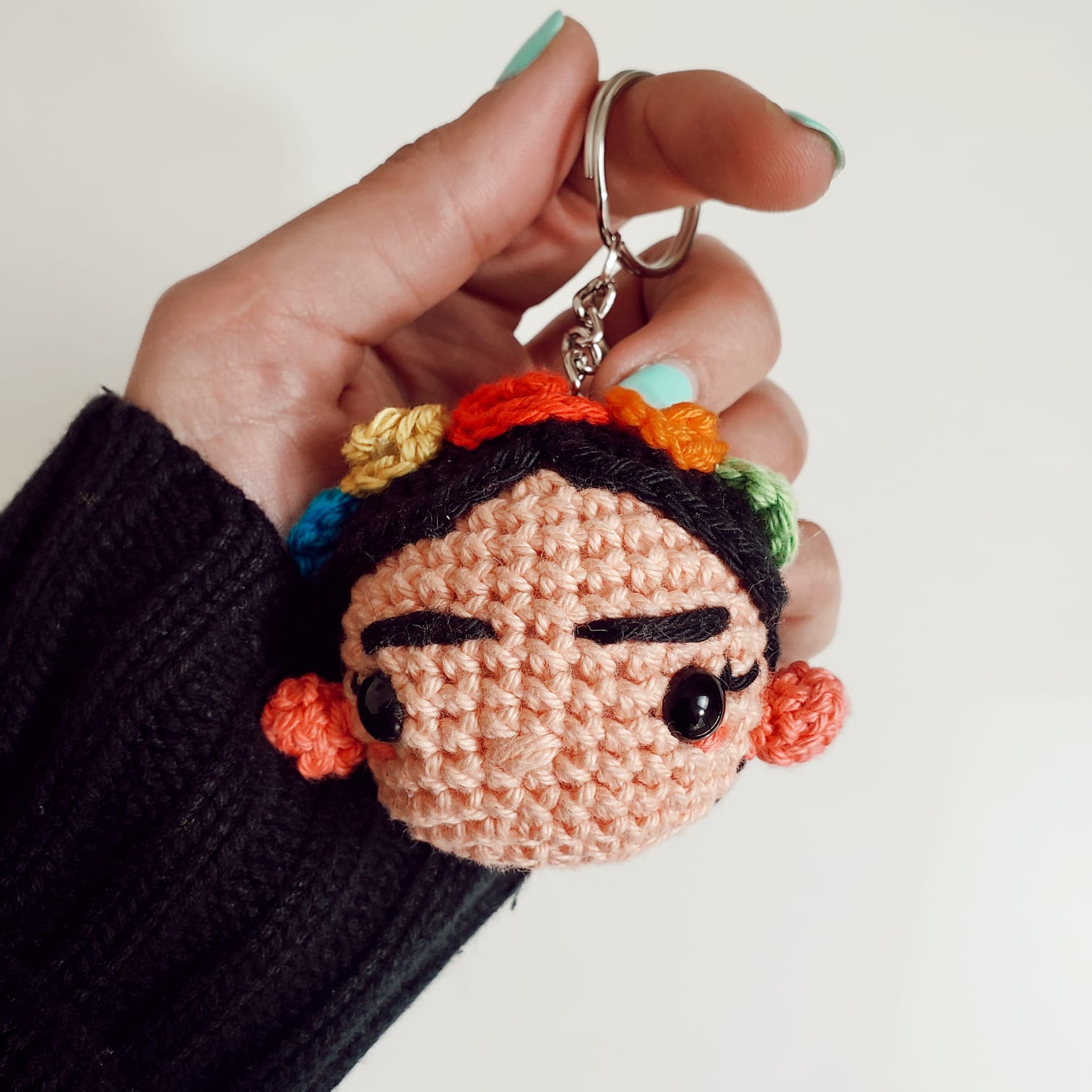 Mano sosteniendo a un Llavero Amigurumi Frida Kahlo