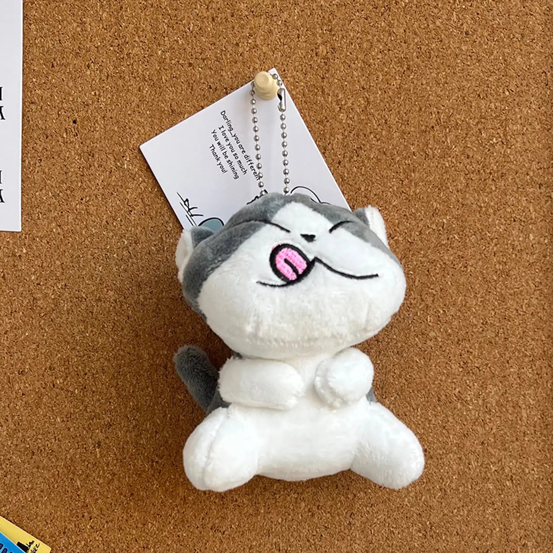 Un llavero de gatito kawaii de peluche colgado en un mural 