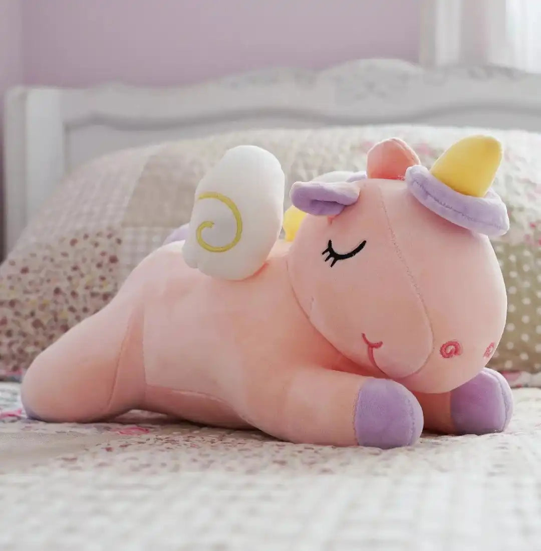 Un peluche en forma de unicornio encima de una cama