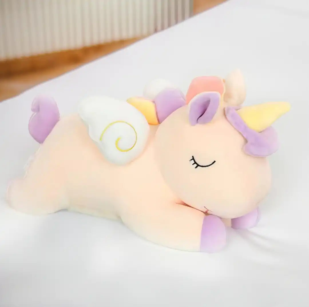 Un peluche en forma de unicornio encima de una cama