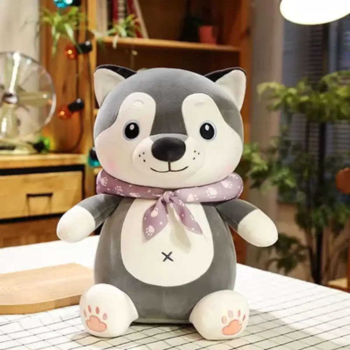 Peluche Perro Kawaii Shiba color gris y blanco con Bufada morada en una habitación